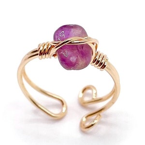 May include: A gold wire wrapped ring with a purple amethyst stone.