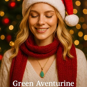 K&ouml;nnte beinhalten: Eine Frau tr&auml;gt einen roten Weihnachtsmannhut, einen Schal und eine goldene Halskette mit einem gr&uuml;nen Aventurin-Anh&auml;nger. Der Text auf dem Bild lautet: "Gr&uuml;ner Aventurin zieht Gl&uuml;ck, F&uuml;lle und neue M&ouml;glichkeiten an."