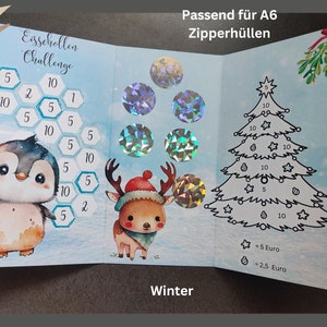 May include: A tri-fold savings challenge card featuring a penguin, a reindeer, and a Christmas tree. The card includes hexagonal fields with numbers, holographic circular stickers, and text reading Eisschollen Challenge, Winter, and Passend f&uuml;r A6 Zipperh&uuml;llen.