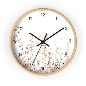May include: A white clock with black hands and black numbers on a wooden frame. The clock face features a watercolor design of pink and brown wildflowers.