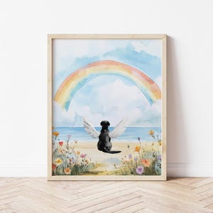May include: A watercolor painting of a black dog with white angel wings sitting on a beach with a rainbow in the sky. The dog is looking up at the rainbow. The painting is framed in a light wood frame.