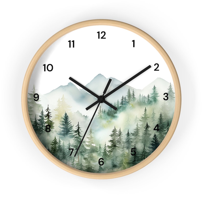 May include: A round wooden framed clock with a watercolor design of a misty forest and mountains. The clock face has black Roman numeral hour markers and black hands.