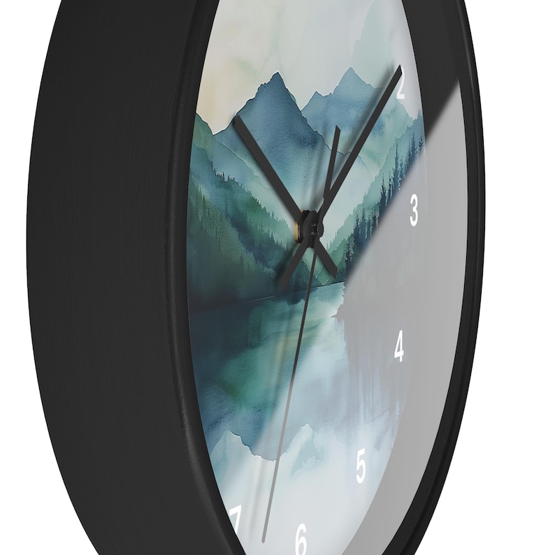 May include: A round black wall clock with a watercolor landscape design. The clock face features a mountain and lake scene in shades of blue and green. The clock hands are black, and the numbers are white.