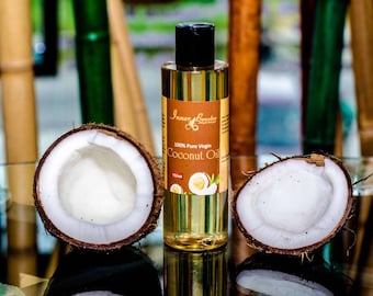 May include: A clear glass bottle of 100% pure virgin coconut oil with a black cap. The bottle is labeled "Inner Beauty" and "Coconut Oil". Two halves of a coconut are on either side of the bottle.