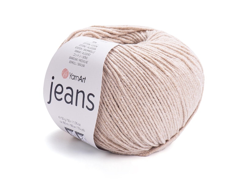 May include: A ball of beige YarnArt Jeans yarn. The label displays the brand name and product details. The yarn is 50g/1.76 oz and approximately 160m/174 yds. The yarn is made of cotton and acrylic.