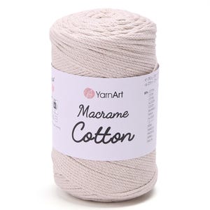 Peut inclure: Une bobine cylindrique de fil de coton YarnArt Macrame blanc cassé. L'étiquette affiche le nom de la marque et les détails du produit. Le fil est étroitement enroulé, montrant une surface texturée. Idéal pour les projets de macramé.