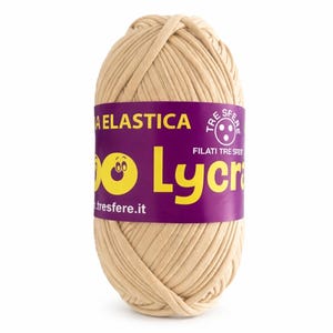 Könnte beinhalten: Beigefarbener Wollknäuel mit einem lila Etikett. Das Etikett zeigt den Text "A Elastica" und "Lycra" in Gelb sowie den Markennamen "Filati Tre Sfer". Das Garn ist eng gewickelt und für Strickprojekte geeignet.