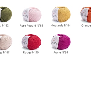 May include: A collection of eight yarn balls in various colors, including green, pink, yellow, orange, beige, red, and purple. Each ball has a label that reads "jeans" and a number. The colors are labeled as Kaki, Rose Poudr&eacute;, Moutarde, Orange, Beige, Rouge, and Prune.