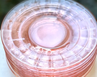 May include: A stack of pink glass dessert plates with a fluted design.