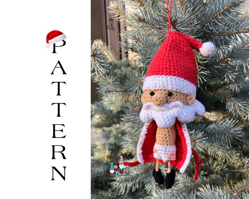 May include: A crocheted Santa Claus ornament with a red hat, white beard, and a red and white cape. The ornament is hanging from a tree branch.
