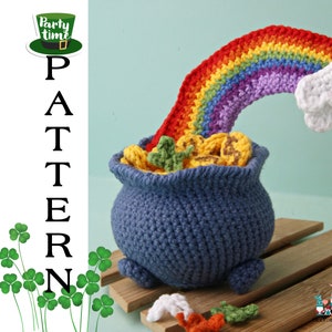 Puede incluir: Una olla de oro de ganchillo con un arcoíris y una nube. La olla es azul y el arcoíris es rojo, naranja, amarillo, verde, azul, añil y violeta. La nube es blanca. La olla está sobre una superficie de madera. El texto "Party time" está en un sombrero verde en la esquina superior izquierda de la imagen. El texto "PATTERN" está en el lado izquierdo de la imagen.