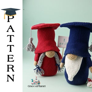 May include: Two crocheted gnomes wearing graduation caps and gowns. The gnome on the left is red and the gnome on the right is blue. The gnome on the right is holding a sign that says "I did it!"