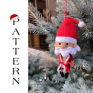 May include: Crocheted Santa Claus ornament hanging from a pine tree branch. The ornament is red and white with a white beard and a red hat. The ornament is a handmade craft.
