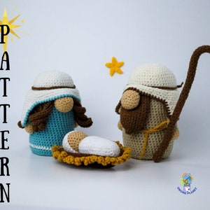 May include: Crocheted nativity scene with a blue and white Mary, a brown and white Joseph, and a white baby Jesus in a yellow manger. A star is in the background.