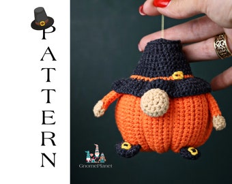 May include: Crocheted pumpkin gnome ornament with a black hat and orange body. The gnome is wearing a black hat with a yellow buckle and has a small, round nose. The gnome is holding a small, yellow pumpkin in its hand.