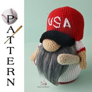 Könnte beinhalten: Gehäkelter Zwerg mit einer roten Baseballkappe mit der Aufschrift "USA" auf der Vorderseite, einem schwarzen Augenklappen und einem weiß-rot gestreiften Hemd. Der Zwerg hält einen braunen Baseballschläger.