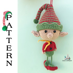 May include: A crocheted elf ornament with a red and green striped hat, green and red striped shirt, and red shoes. The elf is holding a yellow scarf. The ornament is hanging from a green background. GnomePlanet is written in the bottom right corner.