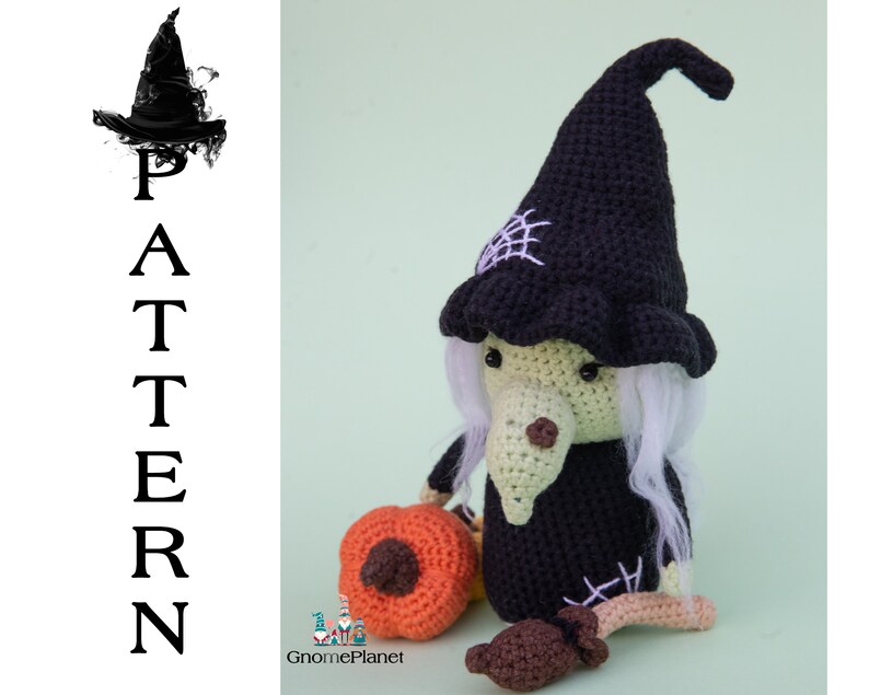 May include: Crocheted witch doll with a black hat, white hair, and a green face. The doll is holding a crocheted orange pumpkin. The doll is sitting on a green background.