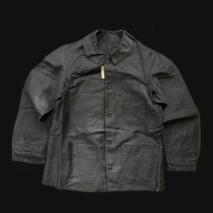 Peut inclure: Veste de travail gris foncé avec un col, une fermeture boutonnée et deux poches poitrine. La veste comporte également deux poches inférieures et des poignets boutonnés. Le tissu a un aspect légèrement texturé.