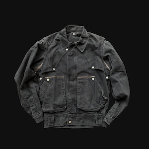 May include: A black denim jacket with a collared neckline, multiple pockets, and zipper details. The jacket has a button-up front and a slightly faded appearance, suggesting a vintage or worn aesthetic. The jacket is a medium weight.