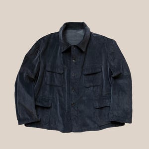 Peut inclure: Veste en velours côtelé bleu marine avec un col et quatre poches avant. La veste a une fermeture boutonnée et une coupe décontractée. Le tissu a une texture côtelée.