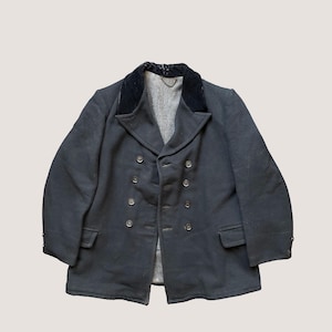 Könnte beinhalten: Eine schwarze, zweireihige Jacke mit Samtkragen. Die Jacke hat einen Knopfverschluss und zwei Taschen.