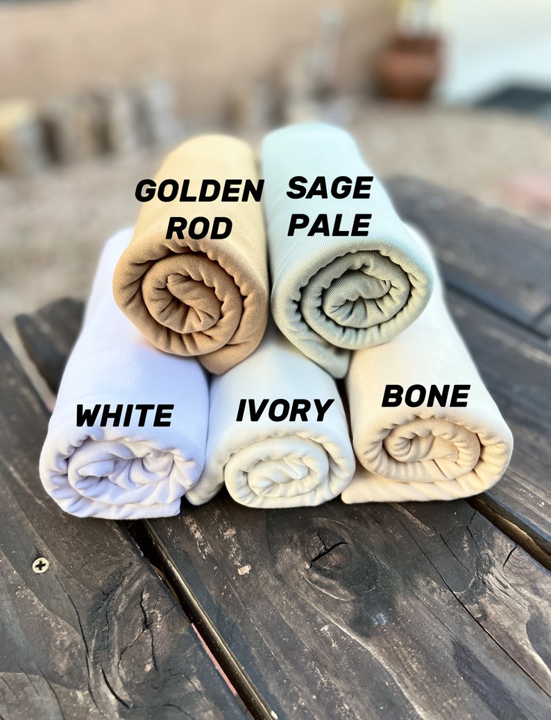 May include: Five rolled up fabric swatches in different shades of white, beige, and green. The swatches are labeled "White", "Ivory", "Bone", "Golden Rod", and "Sage Pale".