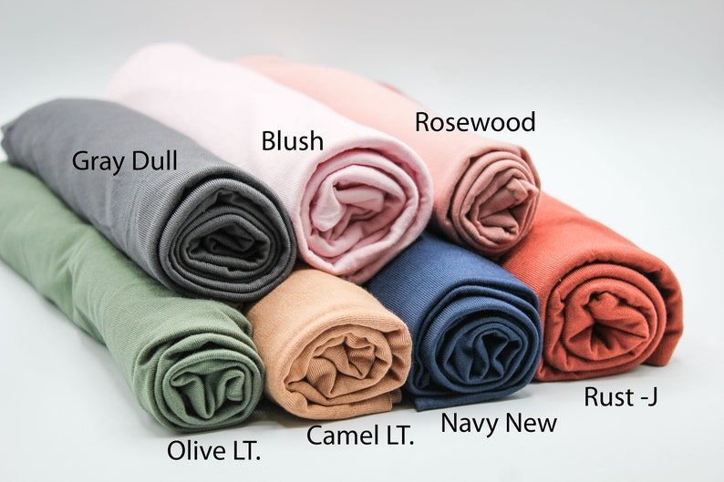 May include: A variety of rolled fabric swatches in different colors, including gray, olive, camel, navy, rosewood, and rust. The fabric swatches are labeled with their color names.