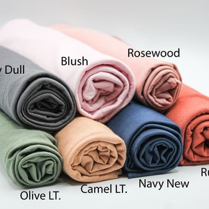 May include: A variety of rolled fabric swatches in different colors, including gray, olive, camel, navy, rosewood, and rust. The fabric swatches are labeled with their color names.