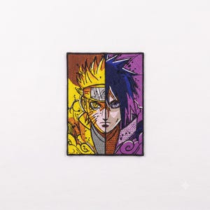 May include: A rectangular embroidered patch featuring a split-face design. The left side depicts a character with spiky yellow hair in shades of orange and gold. The right side shows a character with dark blue hair against a purple background.