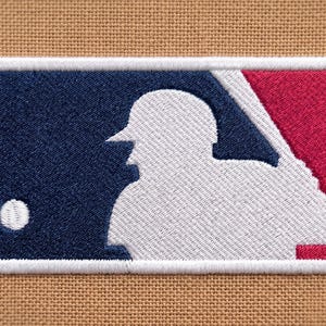 May include: An embroidered Major League Baseball logo patch featuring a white silhouette of a batter on a split navy blue and red background. The rectangular patch has rounded corners, a thick white border, and is stitched onto tan fabric.
