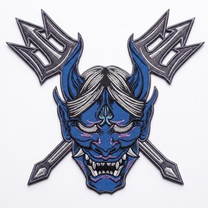 Puede incluir: Un parche bordado que presenta una máscara Hannya azul con cabello blanco y colmillos afilados, colocado frente a dos tridentes plateados cruzados con contornos gris oscuro. El diseño está detallado con hilos negros, blancos y morados.