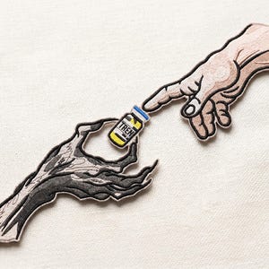 May include: Embroidered patch featuring a skeletal hand reaching for a vial labeled "TREN" held by a flesh-toned hand. The design mimics the Creation of Adam, with the hands nearly touching. The vial is yellow with blue and white accents.