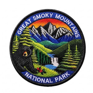 May include: A circular embroidered patch featuring a black bear in the foreground, a waterfall, green pine trees, and snow-capped mountains under a sunset sky. The text "GREAT SMOKY MOUNTAINS NATIONAL PARK" is stitched in white along the border.
