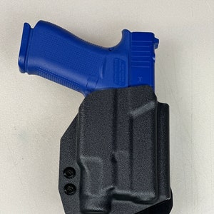 May include: A black polymer holster with two screws for a blue handgun. The holster has a belt clip and a flared magazine well.
