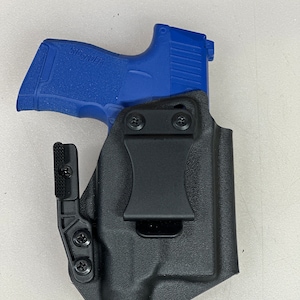 May include: A black leather holster with a blue polymer handgun inside. The holster has a clip on the side for attaching to a belt.