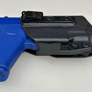 Puede incluir: Una funda de pol&iacute;mero negra con un clip y una inclinaci&oacute;n ajustable. La funda est&aacute; dise&ntilde;ada para adaptarse a una pistola con un marco de pol&iacute;mero azul.