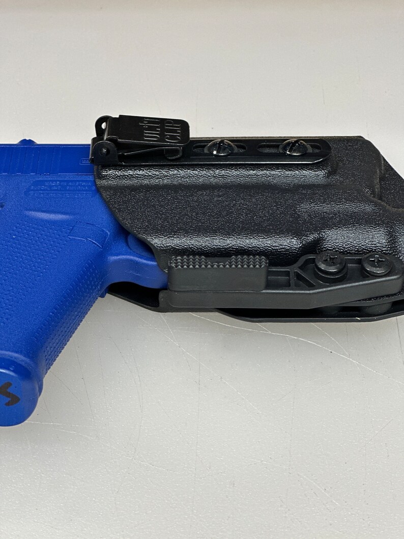 Puede incluir: Una funda de pol&iacute;mero negra con un clip y una inclinaci&oacute;n ajustable. La funda est&aacute; dise&ntilde;ada para adaptarse a una pistola con un marco de pol&iacute;mero azul.