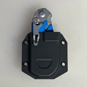 May include: A black leather holster with a blue and silver multi-tool inside. The holster has a snap closure and is designed to be worn on a belt.