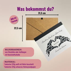 May include: A white card with black text that reads "Hand in Hand a Life Long" with a black heart made of smaller hearts. The date "06.01.2028" and the names "Simone & Johannes" are also printed on the card. The card is 31.5 cm by 22.5 cm and comes with a brown cardboard frame.