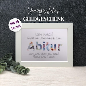 Könnte beinhalten: Ein weißer Rahmen mit einem weißen Passepartout und einer gedruckten Nachricht, die "Liebe Maria! Herzlichen Glückwunsch zum Abitur Wir sind stolz auf dich! Mama und Klaus" lautet. Das Wort "Abitur" ist aus buntem Papiergeld gefertigt.