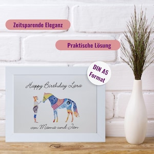 May include: A white framed print in DIN A5 format featuring a graphic of a person standing next to a horse, both filled with a colourful patterned design. The text reads Happy Birthday Lara and von Mama und Jan. Above are labels Zeitsparende Eleganz and Praktische L&ouml;sung.