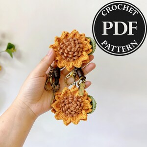 Puede incluir: Llaveros de girasol hechos a mano con ganchillo, con correas de cuero marrón y herrajes color bronce. Los girasoles son en tonos amarillos y marrones, con hojas verdes. El texto "CROCHET PDF PATTERN" es visible.