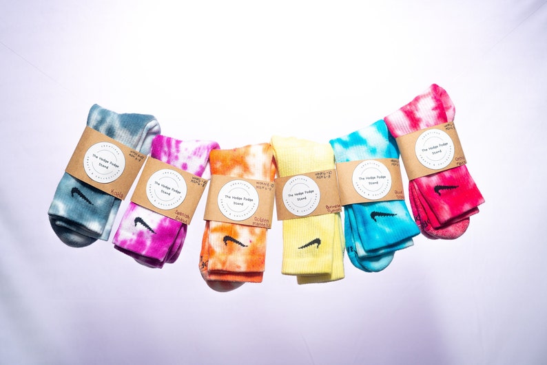K&ouml;nnte beinhalten: Sechs Paar bunte Batik-Socken mit einem schwarzen Nike-Swoosh-Logo. Jedes Paar hat ein braunes Papieretikett mit dem Text "The Vintage Fudge Stand" in einem Kreis.