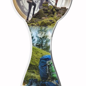 May include: A clear glass trophy with a compass face on top. The compass face has a black needle pointing north. The trophy has a black base and a clear glass body with a photo of two people hiking in the mountains. The photo shows a green forest and a blue sky.
