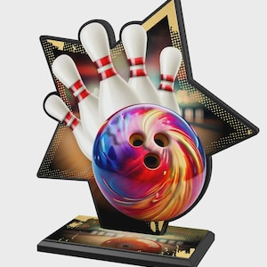 May include: A bowling trophy featuring a colorful bowling ball and white bowling pins with red stripes, set against a star-shaped background. The trophy sits on a black base with gold accents, showcasing a bowling alley scene.