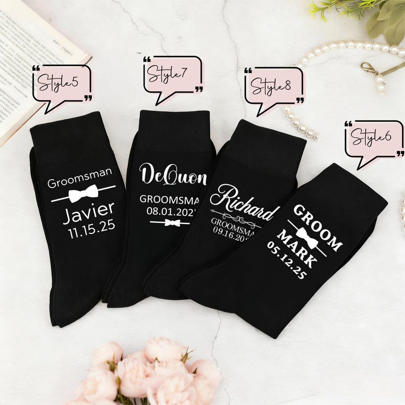 May include: Four black socks featuring white printed text and bow tie graphics. The socks display names such as Javier, DeQuon, Richard, and Mark, along with dates and titles like Groomsman and Groom. Each sock is labeled with a speech bubble style tag.