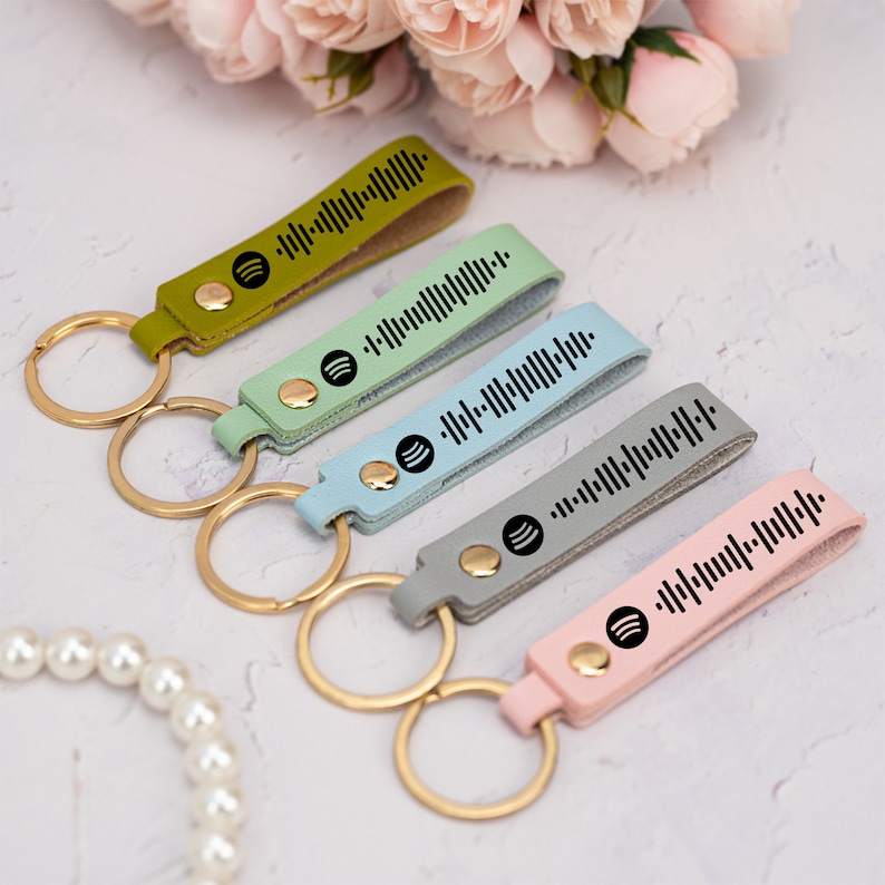 May include: Five keychains with different colored leather straps and gold key rings. Each strap has a black Spotify logo and a barcode-like design.