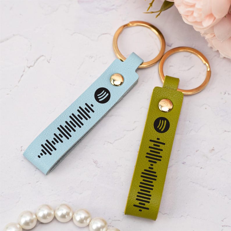 May include: Two leather keychains with gold key rings. One keychain is light blue with a black Spotify barcode and the other is green with a black Spotify barcode.