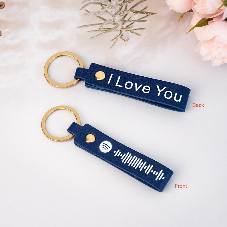 May include: A blue leather keychain with a gold ring. The front side features a white Spotify logo and a barcode. The back side says "I Love You".